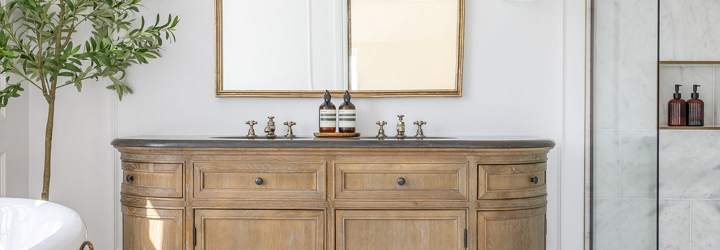 Elegant bathroom with Carrara Bianco marble tiles with a rustic wooden vanity, large mirror, marble shower, and bright window. A potted plant and basket add natural elements. Serene ambiance.