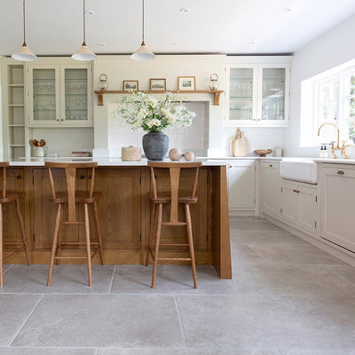 Hambleton Taupe kitchen floor tiles with a wooden island and vase with flowers