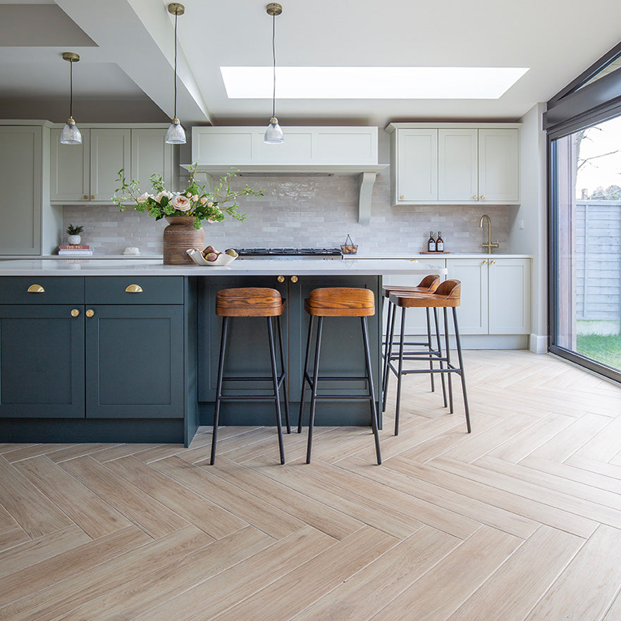 A kitchen with a bar and stools with Falmouth Sandy Oak herringbone floor
