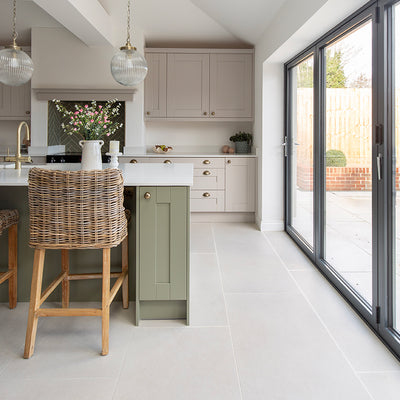 Frome White Stone effect tiles in a kitchen featuring a green island and a rattan stool 